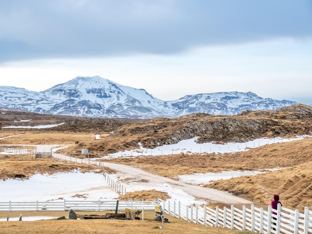 Champ avec de la neige en hiver avec des montagnes en arrière-plan sous un ciel bleu nuageux en Islande