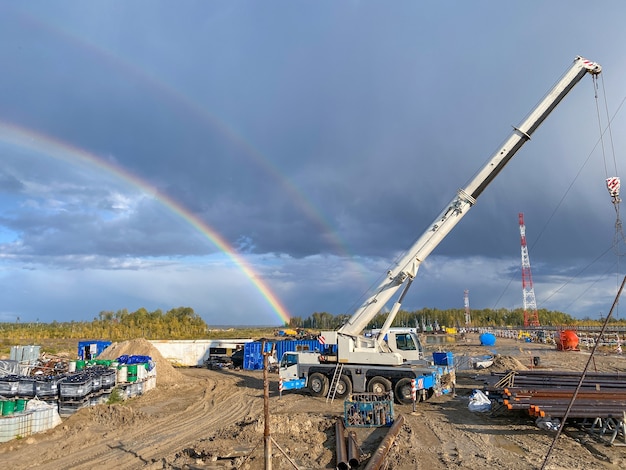 Champ de pétrole au nord, arc-en-ciel en arrière-plan. Machines de travail sur l'installation de forage.