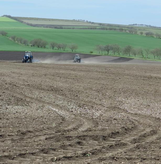 Un champ avec un tracteur et un champ avec un champ vert en arrière-plan.