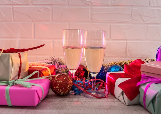 Champagne dans des verres sur une table en bois avec des cadeaux de Noël colorés