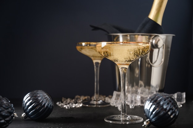 Champagne du nouvel an dans des verres à vin et une bouteille dans un seau décoré de boules bleues de noël