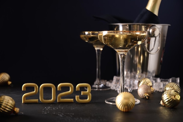 Photo champagne du nouvel an dans des verres à vin et une bouteille dans un seau décoré de boules d'or de noël