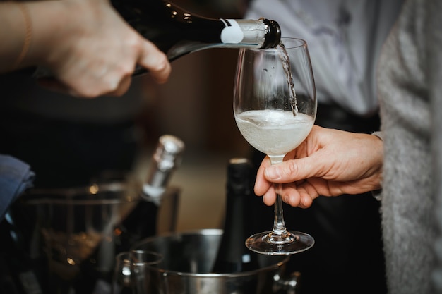 Le champagne est versé dans un verre au visiteur.