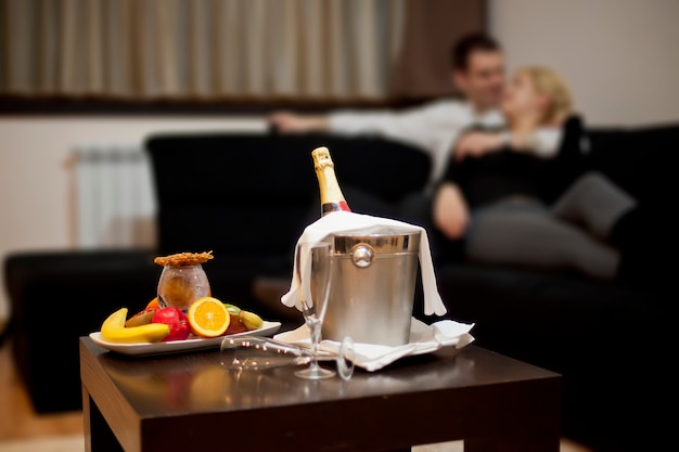 Champagne et fruits sur table. Couple, baisers, Sofa