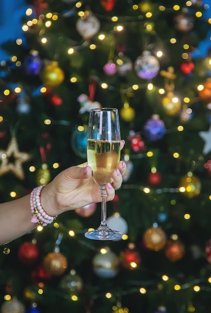 Champagne à la main contre le sapin de Noël