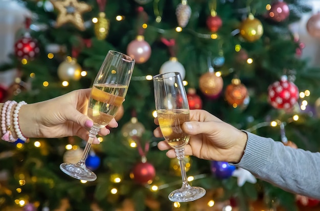 Champagne à la main dans le contexte de l'arbre de Noël. Gens.