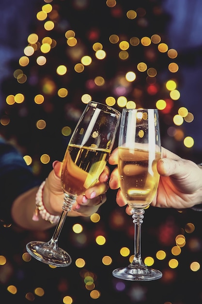 Champagne à la main sur le fond de l'arbre de Noël