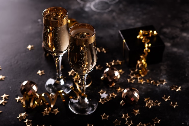 Photo champagne de noël, bulles de gaz, confettis et lumières floues sur fond sombre