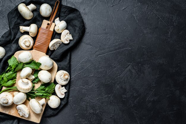 Champignon de champignons crus sur une planche à découper en bois.