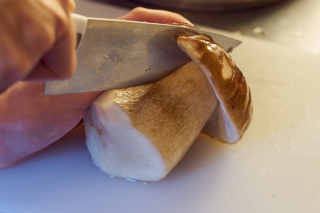 Le champignon forestier est coupé avec un couteau sur la planche.