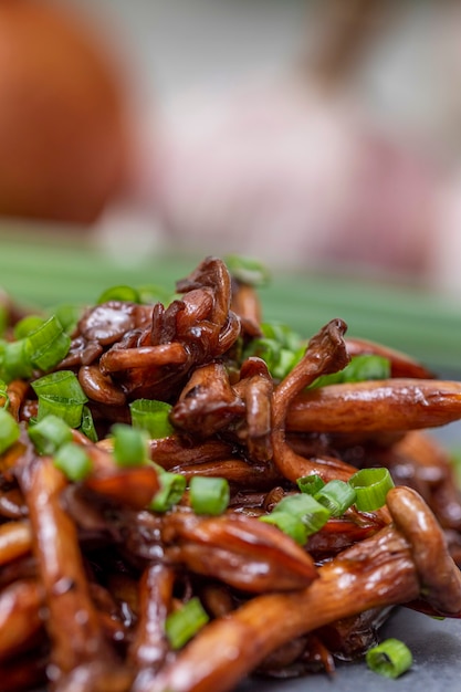 Champignon Shimeji servi avec de la ciboulette sur plaque de pierre noire. Repas oriental typique. Détail du plat de nourriture, gros plan, mise au point sélective.