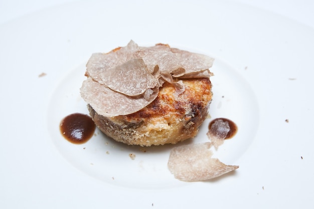 Photo champignon truffe blanche glisser sur la nourriture dans une assiette blanche. le champignon à la truffe blanche est la reine du champignon.