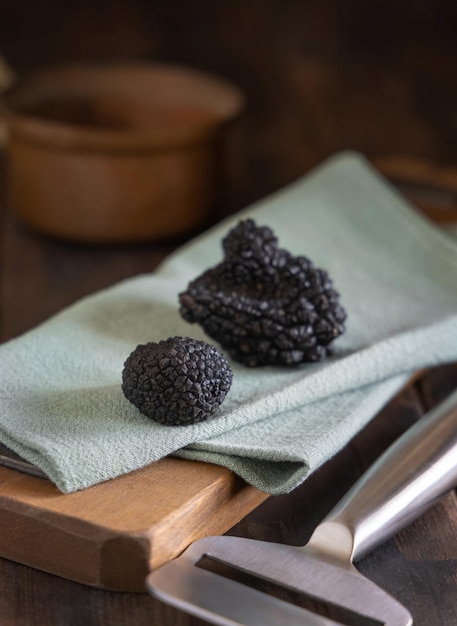 Champignon truffes noires entières sur planche de bois sur serviette verte close up