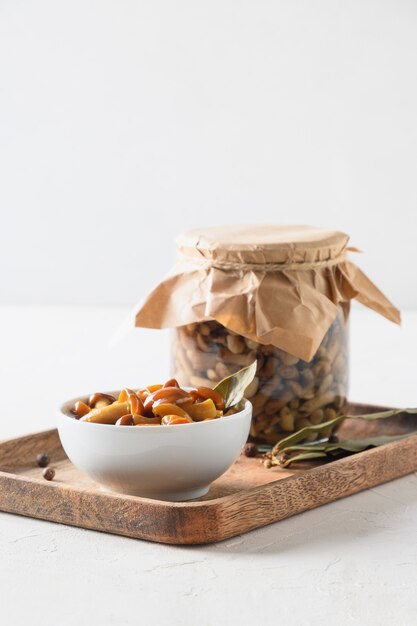 Champignons au miel marinés dans un bol et un pot sur fond blanc