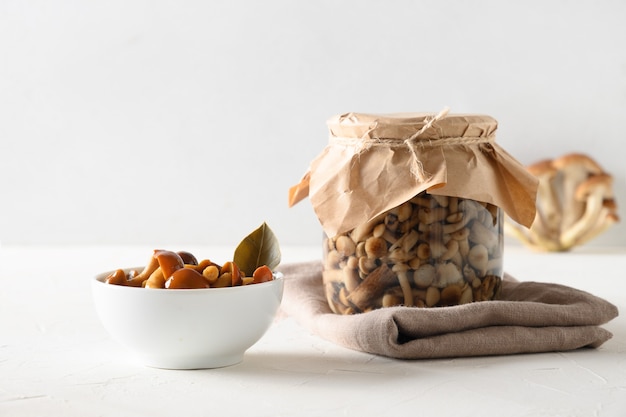 Champignons au miel marinés dans un bol et un pot sur fond blanc