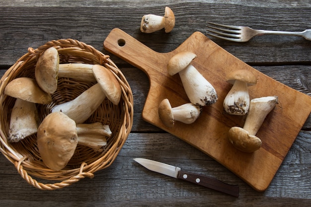 Photo champignons blancs frais dans le panier pour la cuisson sur une planche de bois.