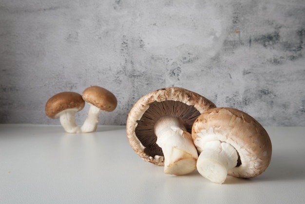 Champignons à capuchon brun sur la table contre le gros plan de mur de texture