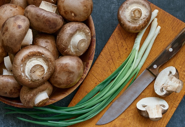 Champignons champignon dans un bol en bois et oignons verts, gros plan