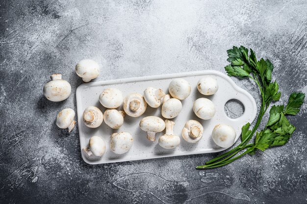 Champignons champignon frais sur une planche à découper blanche. Vue de dessus.