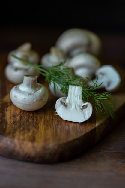 Champignons champignons crus sur planche de bois sombre