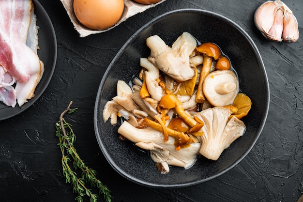 Photo champignons en conserve dans l'huile, sur fond noir, vue de dessus à plat