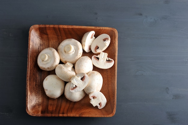 Champignons crus entiers et hachés sur un bois