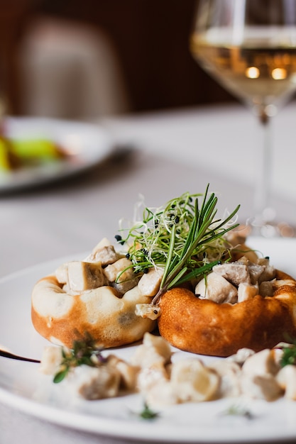 Champignons farcis remplis de fromage, tige de champignon et microgreen sur la plaque blanche avec un verre de vin dans le restaurant