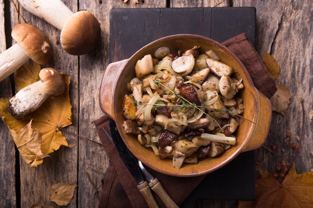 Champignons forestiers frits, cèpes, oignons. Plat rustique dans une poêle, nourriture végétarienne d'automne sur le dessus de la vue