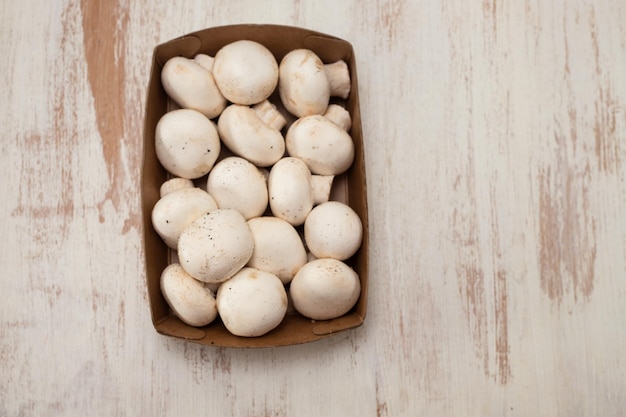 Champignons frais en boîte sur gris