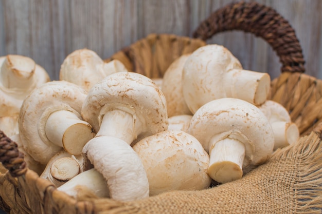 Champignons frais dans un panier en osier sur fond de bois foncé