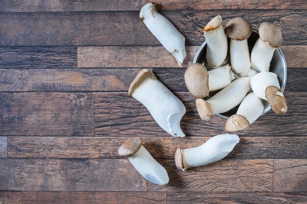 Champignons frais dans une tasse sur un fond en bois.