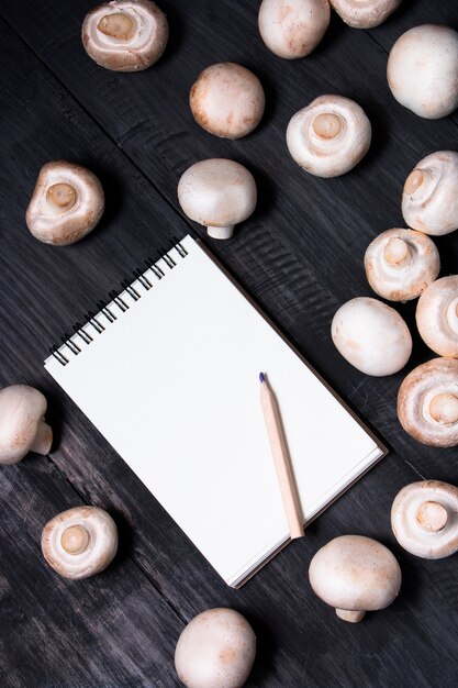 Champignons frais et note pour enregistrement sur table noire