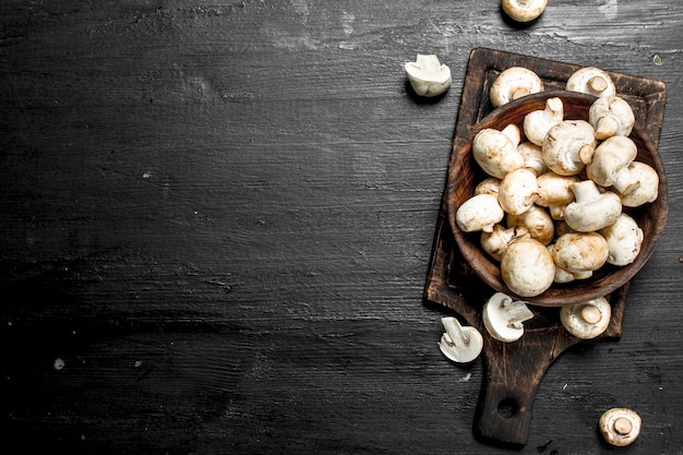 Champignons frais sur le plateau. Sur le tableau noir.