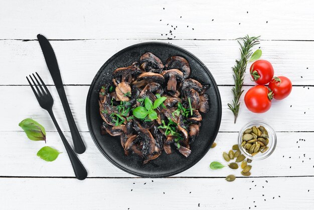 Champignons frits au persil dans une assiette Sur un fond en bois blanc Vue de dessus Espace libre pour votre texte