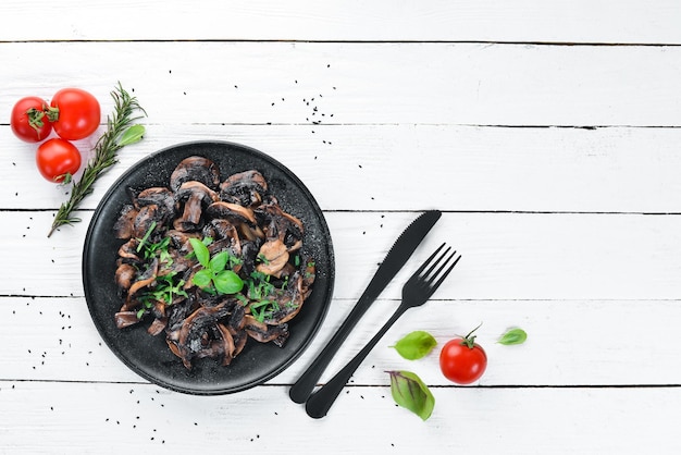 Champignons frits au persil dans une assiette Sur un fond en bois blanc Vue de dessus Espace libre pour votre texte