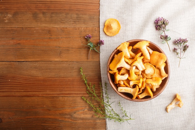 Champignons girolles dans un bol en bois et herbes aromatiques avec textile en lin. Vue de dessus.