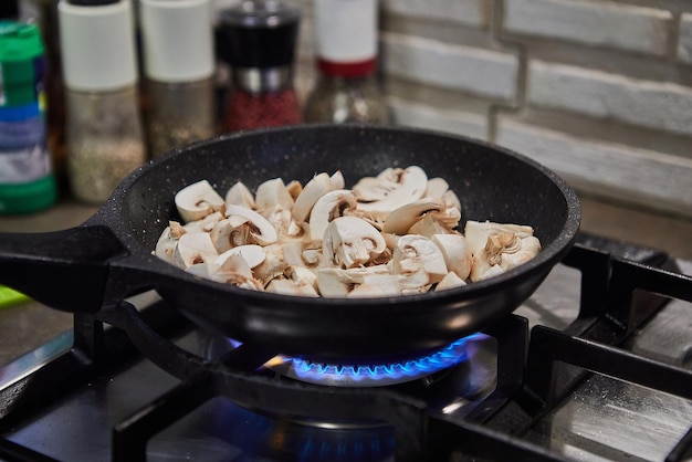 Les champignons hachés sont frits dans une poêle à frire sur une cuisinière à gaz