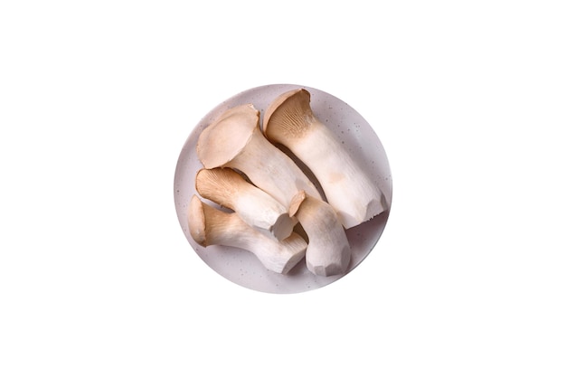 Champignons Pleurotus eryngii sur fond de béton foncé Champignons comestibles entiers crus