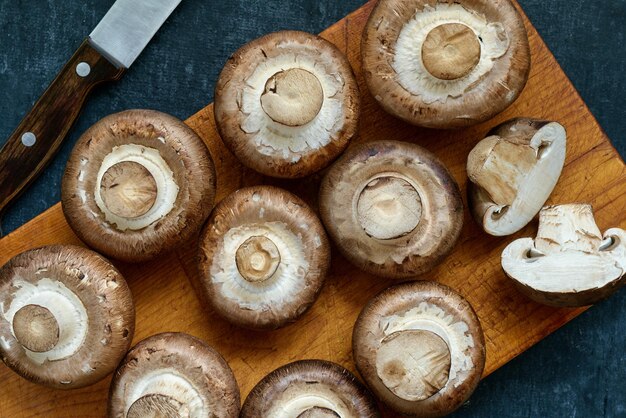 Champignons royaux non cuits frais sur une planche à découper en bois vue de dessus gros plan