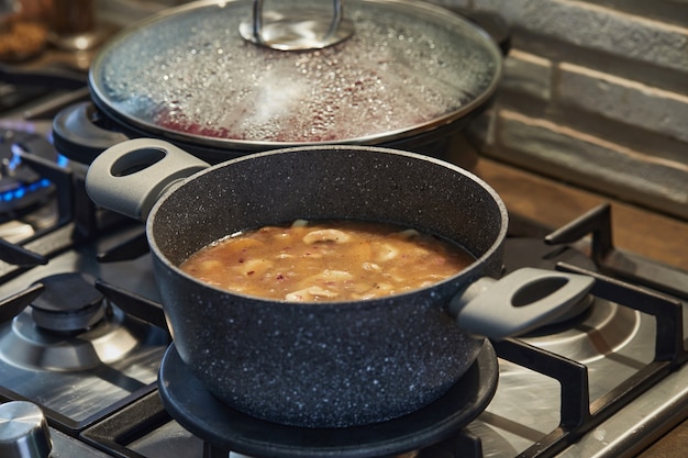 Champignons en sauce dans une casserole sur cuisinière à gaz dans la cuisine.