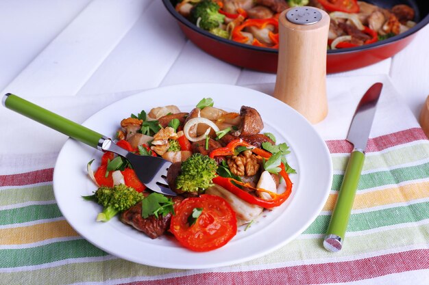 Champignons sauvages braisés avec légumes et épices dans une poêle et assiette sur table