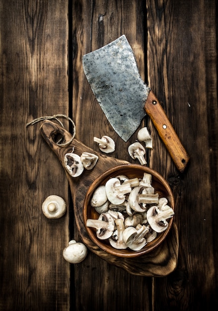 Champignons tranchés dans une tasse en bois sur l'ancien conseil. Sur table en bois.