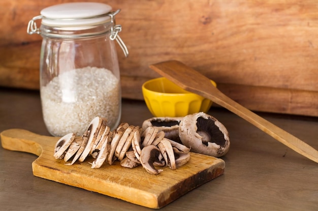 Champignons tranchés sur une planche de bois et un pot de riz sur un comptoir de cuisine