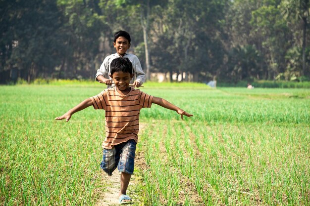 Photo les champs agricoles du bangladesh deux enfants dansent joyeusement sur le chemin village puijor ville rajbari bangladesh capture 522023