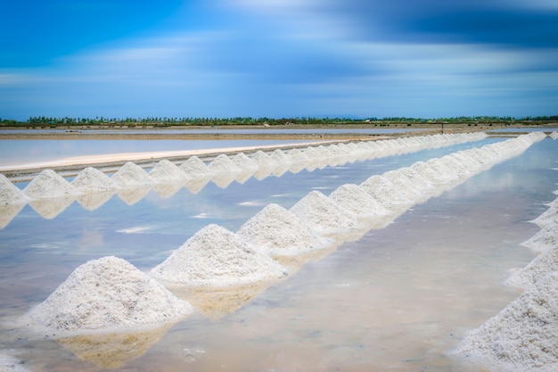 Champs de sel de mer avec du sel empilé sur fond de ciel bleu en Thaïlande.