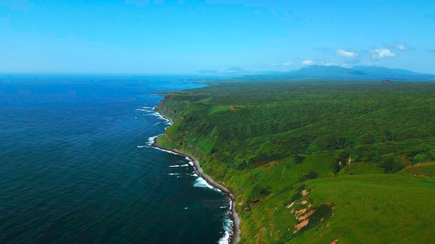 Des champs verts, des prairies d'été, un ciel bleu et une mer calme, une campagne pittoresque, un paysage marin avec