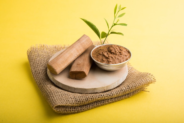 Chandan ayurvédique ou pâte de bois de santal dans un bol en argent avec des feuilles de bâtons et de feuilles placées sur sahanor sahana ou une base en pierre circulaire pour créer de la pâte