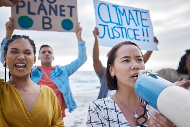 Photo le changement climatique du mégaphone et une femme asiatique protestent avec la foule à la plage pour protester contre l'environnement et le réchauffement climatique sauvez l'activisme du groupe de la terre et les gens crient sur le mégaphone pour arrêter la pollution