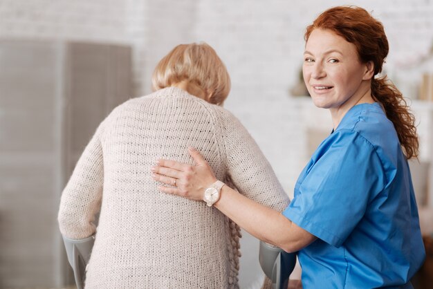 Changement de génération. Une infirmière professionnelle qualifiée rend visite à une femme âgée et marche avec elle tout en s'assurant qu'elle se sent bien