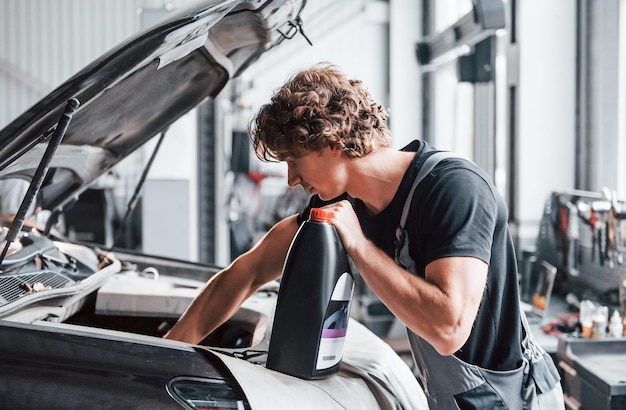 Photo changement d'huile homme adulte en uniforme de couleur grise travaille dans le salon de l'automobile